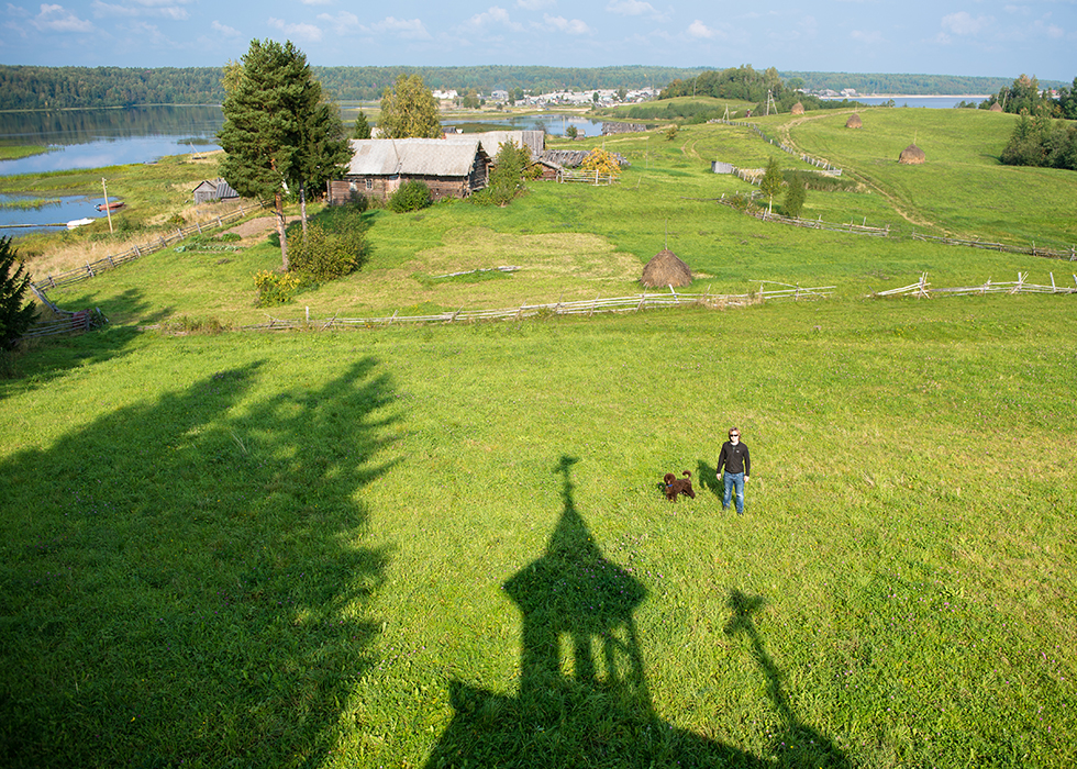 Тень часовни Николая Чудотворца и вид на поселок Усть-Поча в Кенозерском национальном парке.